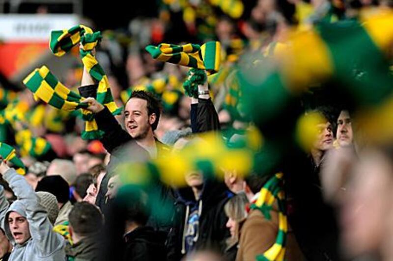 Manchester United fans opposed to the Glazers wave yellow and green scarves during a Premier League match at Old Trafford.