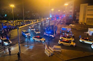 Crowds line the streets as a parade of police cars and taxis enter Al Ras and Naif on Sunday night. Officials played the national anthem and thanked residents for their cooperation after an almost month-long lockdown. The National