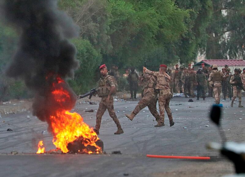 An Iraqi officer directs a soldier's weapon away from anti-government protesters during a demonstration in Baghdad, Iraq. AP