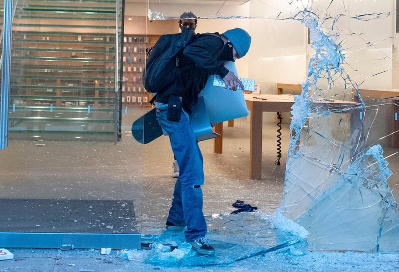A man takes an iMac through the broken window of the Apple store at the Grove shopping center in the Fairfax District of Los Angeles. AFP