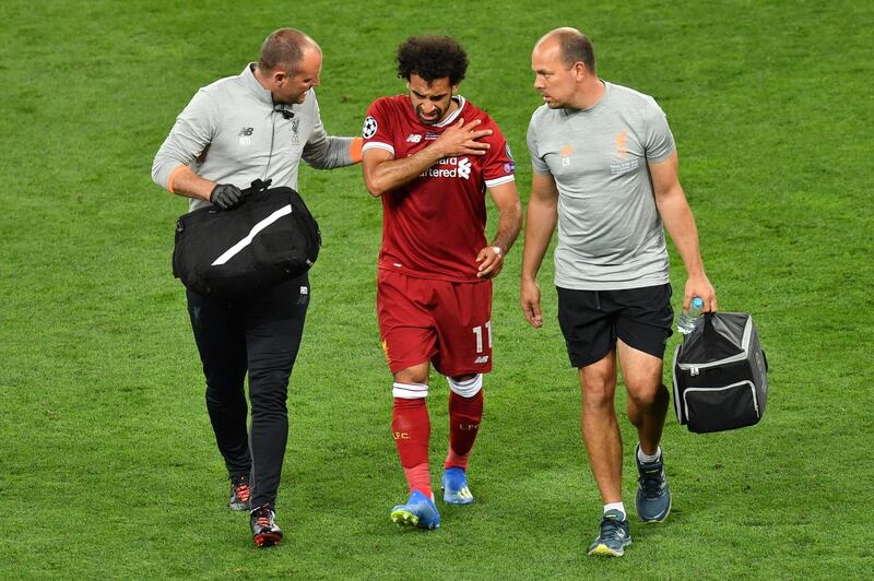 (FILES) In this file photo taken on May 26, 2018 Liverpool's Egyptian forward Mohamed Salah (C) gets medical assistance as he leaves the pitch following injury during the UEFA Champions League final football match between Liverpool and Real Madrid at the Olympic Stadium in Kiev, Ukraine. Elite footballers face ever-increasing physical and mental demands, with a faster-paced game and long, gruelling seasons. In a World Cup year, how does a player make it to June fit and fired up? It is actually quite difficult, the experts say, and requires an army of dedicated specialists tracking and carefully engineering each athlete's mental and physical condition. A similar fate has now befallen Egypt, with star striker Mohamed Salah injuring a shoulder while playing for Liverpool in the Champion's League final on May 26. / AFP / Sergei SUPINSKY
