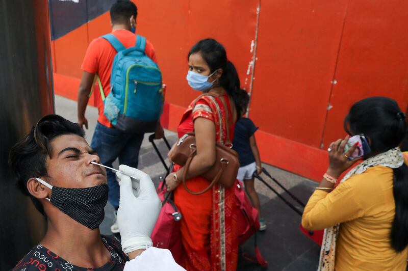 A healthcare worker collects a swab sample at a railway station, in New Delhi, India. Reuters