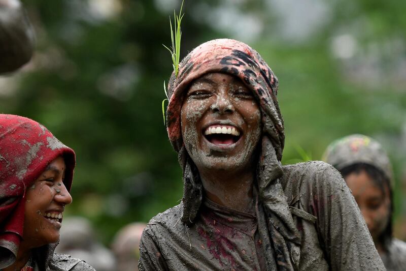 A woman smiles in a rice paddy field during "National Paddy Day", which marks the start of the annual rice planting season, in Tokha village on the outskirts of Kathmandu.  Farmers in Nepal celebrate National Paddy Day as the annual rice planting season begins. AFP