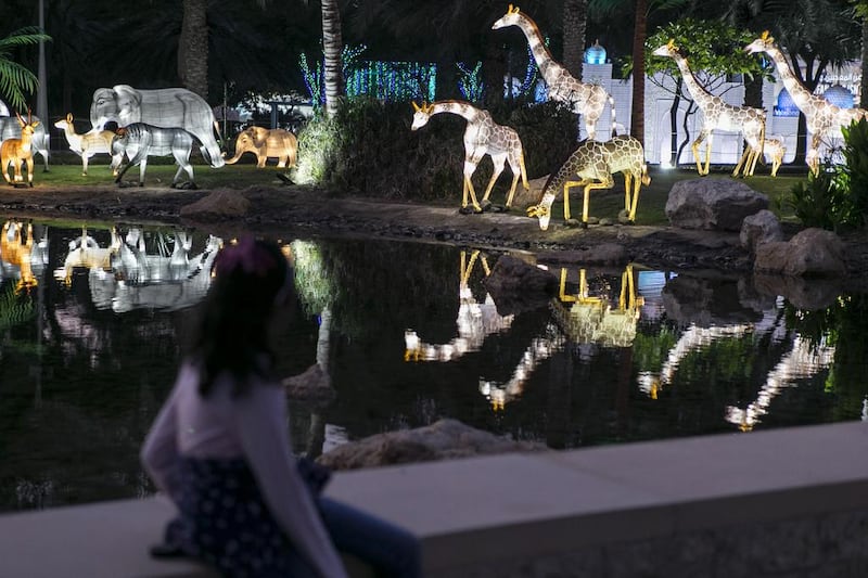 A girl looks at a glowing animal enclosure. Reem Mohammed / The National