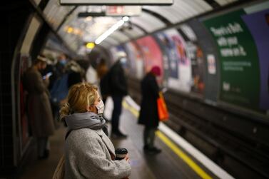 A woman wearing a face mask and holding a cup looks on at the Vauxhall tube station in London. Reuters.