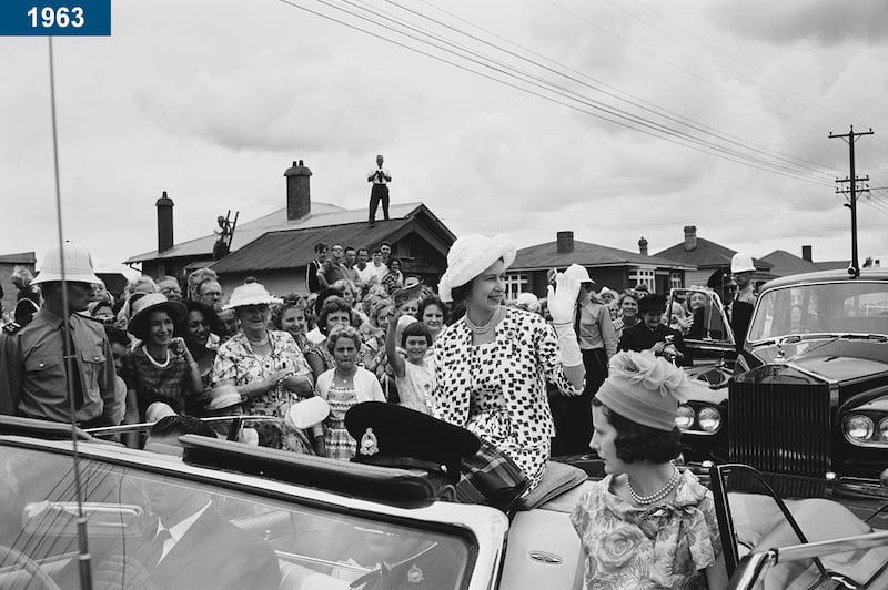 1963: The queen waves to residents from the rear of an open top car in the town of Russell, during a Commonwealth visit to New Zealand.