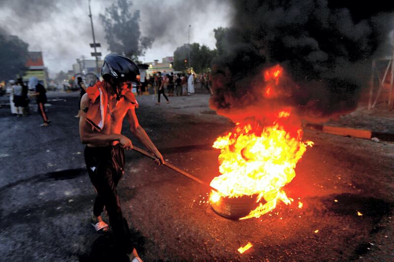 An Iraqi demonstrator burns tires to block the road during a protest over poor public services in the holy city of Najaf, Iraq July 26, 2020. REUTERS/Alaa Al-Marjani