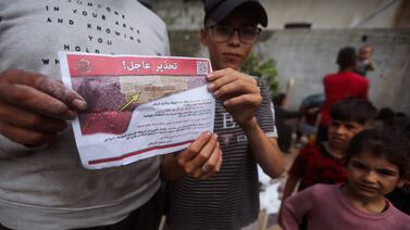 Palestinians hold leaflets dropped from planes that ordered them to leave eastern Rafah before an Israeli military operation. AP