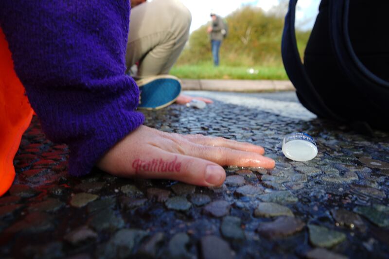 A protester glues their hand to the road in Manchester.