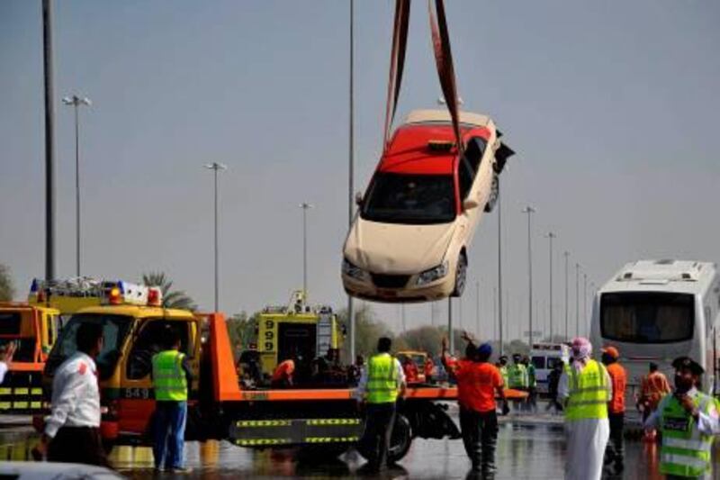 RESTRICTED TO EDITORIAL USE - MANDATORY CREDIT " AFP PHOTO / HO / WAM - NO MARKETING NO ADVERTISING CAMPAIGNS - DISTRIBUTED AS A SERVICE TO CLIENTS 
A picture released by the Emirati news agency WAM late on April 2, 2011 shows policemen and rescue workers removing a car involved in a massive pile-up of 127 vehicles on the motorway linking Abu Dhabi and Dubai after a speeding car collided into another in foggy conditions, leading to a chain of vehicles crashing into each other. One man was killed and 61 others were injured. AFP PHOTO/HO/WAM
 *** Local Caption ***  693913-01-08.jpg