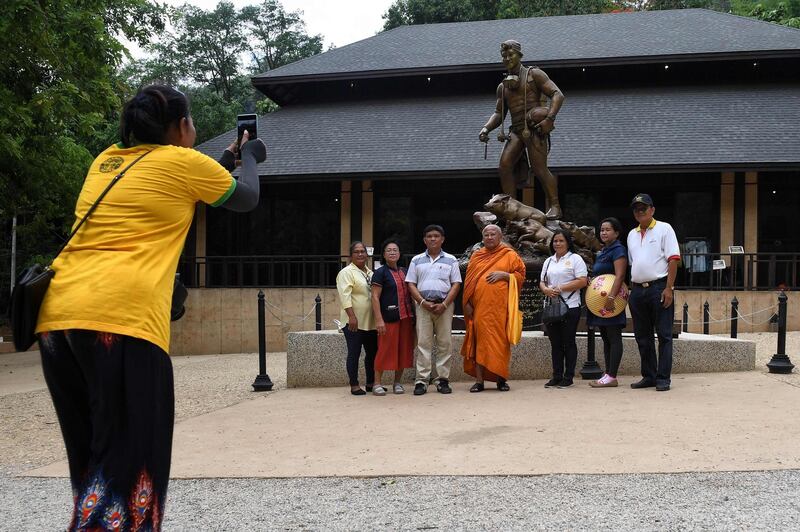 This picture taken shows visitors posing for photos in front of a statue of Saman Gunan, the Thai diver who died during the efforts to rescue the boys and their coach. AFP