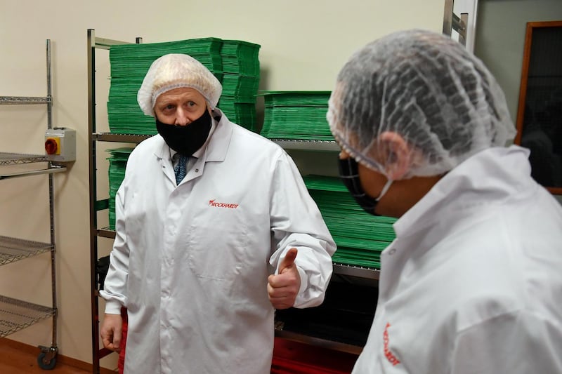 Britain's Prime Minister Boris Johnson (L), wearing a hair net and face covering reacts as he views the last minute quality testing of the 'fill and finish' stage of the manufacturing process of COVID-19 vaccines, during his visit to Wockhardt's pharmaceutical manufacturing facility in Wrexham, north Wales, on November 30, 2020. - Britain's Government in August announced a deal with global pharmaceutical and biotechnology company Wockhardt, to increase capacity in a crucial part of the manufacturing process for Covid-19 vaccines. Britain has been Europe's worst-hit country during the pandemic, recording more than 57,000 deaths from some 1.6 million cases. (Photo by Paul ELLIS / various sources / AFP)