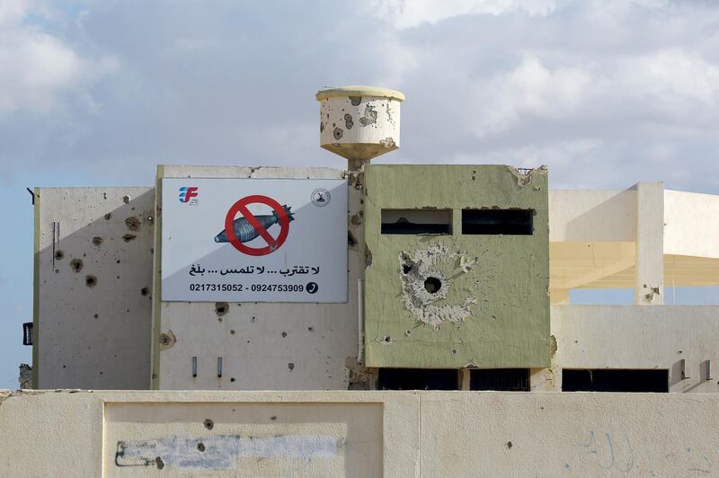 A rocket-riddle building with a sign in Arabic calling for people to stay away from unexploded devices is seen in Tawergha, 260 km east of the Libyan capital Tripoli, on November 9, 2018. Displaced families from Tawergha, a town which sided with Libya's leader Moamer Kadhafi before his ouster in a 2011 revolt, have been able to return to their homes after seven years following an agreement on a deal that allowed civilians to return to their hometown.. / AFP / Mahmud TURKIA
