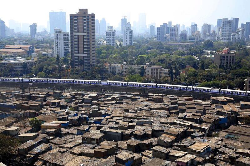 A train passes through slum area of Mumbai, a city that is too costly for the many poor people living there. The government now says affordable housing will receive infrastructure status. Rajanish Kakade / AP Photo