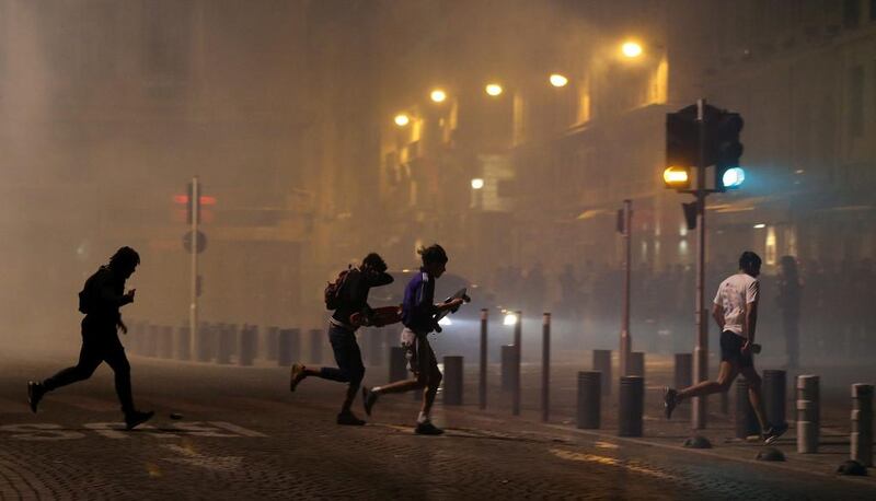 People run after police use tear gas to disperse soccer fans during clashes following the UEFA EURO 2016 group B soccer match between England and Russia in the port of Marseille, France. Tolga Bozoglu / EPA