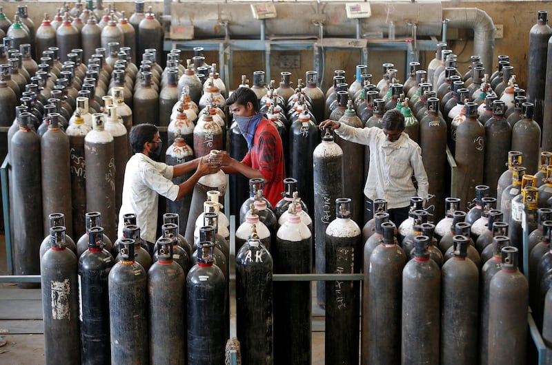 People carry oxygen cylinders after refilling them in a factory, amidst the spread of the coronavirus disease (COVID-19) in Ahmedabad, India, April 25, 2021. REUTERS/Amit Dave