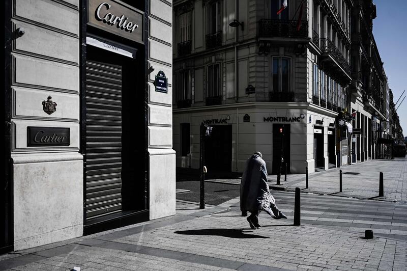 This picture taken on March 23, 2020 shows a homeless person walking down the deserted Champs Elysees in Paris, during the strict lockdown in France to stop the spread of the COVID-19 novel coronavirus.  / AFP / Philippe LOPEZ
