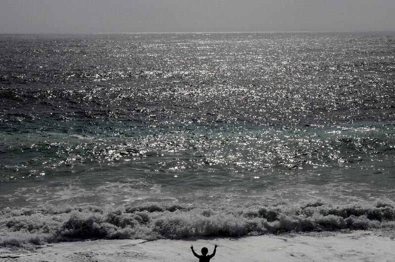 A child gestures towards waves of the Mediterranean Sea as they break on the shore of the French Riviera city of Nice. AFP