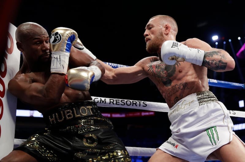 Conor McGregor, right, hits Floyd Mayweather. AP