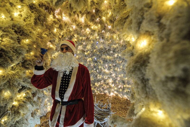 A man dressed as Santa Claus rings a bell while standing inside the giant Christmas tree set up in Iraq's predominantly Christian town of Qaraqosh, in northern Nineveh province. AFP