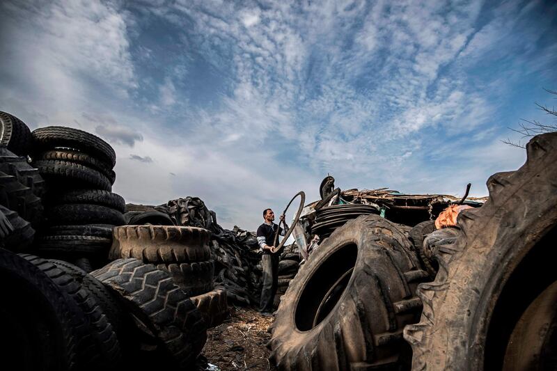A labourer carries a deconstructed tyre piece amidst stacked tyres at a rubber recycling workshop in the village of Mit al-Harun in Egypt's central Nile delta Gharbia Governorate, about 70 kilometres (43 miles) north of the capital.  AFP