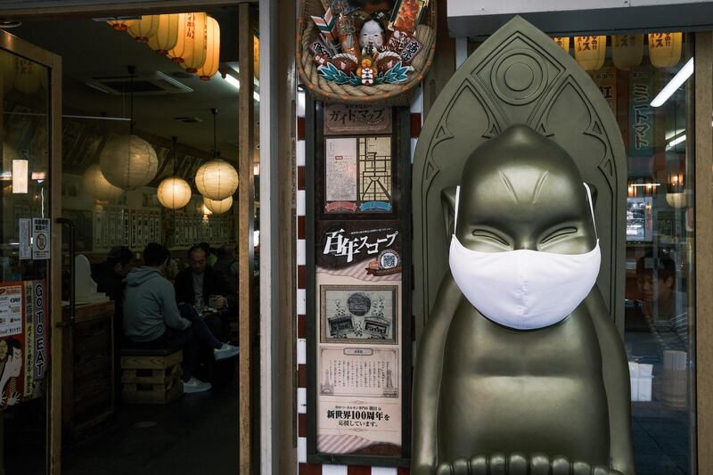 A statue in front of a restaurant wears a protective mask in the Shinsekai shopping district of Osaka, Japan. Bloomberg