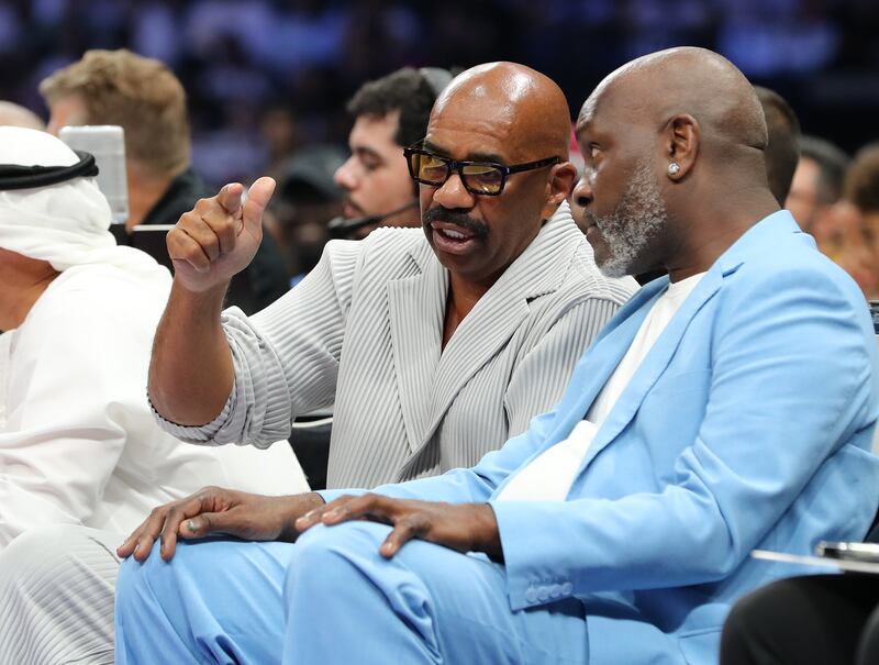 Steve Harvey chats with former NBA player Gary Payton, right, during the first game between the Minnesota Timberwolves and Dallas Mavericks