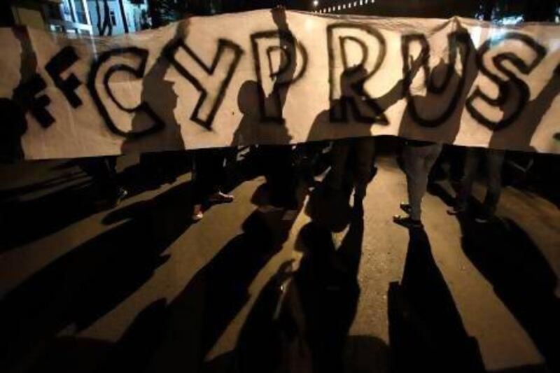 Protesters hold a banner that reads "Hands off Cyprus" during an anti-bailout rally outside European Union house in Nicosia.