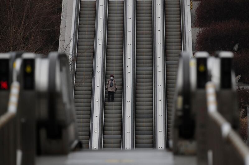 A lone woman takes the escalator down in Seoul. AP Photo