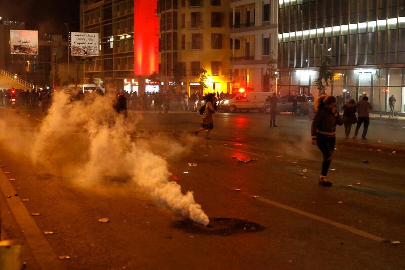 Protesters cover their faces from the tear gas that fired by the riot police during an anti-government protest in Beirut, Lebanon. AP Photo