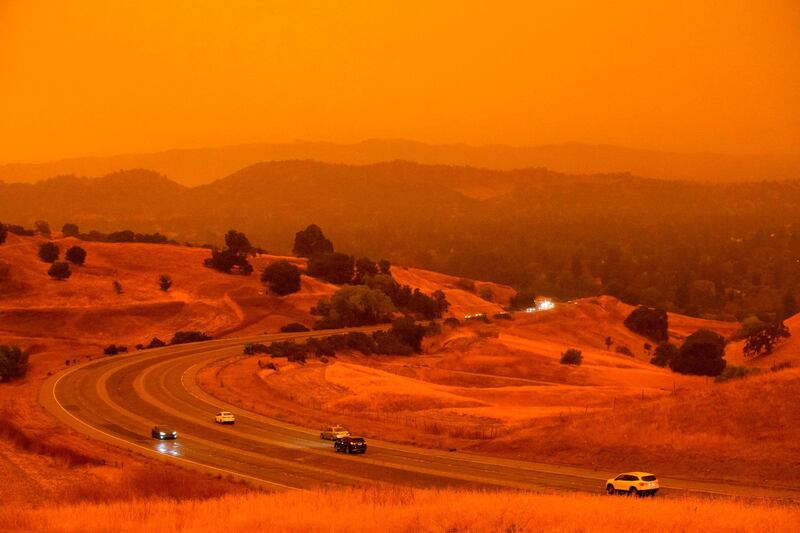 Cars drive along Ygnacio Valley Road below an orange sky filled with wildfire smoke  in Concord, California, as a hazy-looking Walnut Creek can be seen in the distance through the smoke. AFP