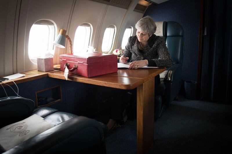 Britain's prime minister Theresa May sits with her ministerial case at a desk aboard a Royal Air Force (RAF) aircraft as she is flown from Northern Ireland to Barry in south Wales. Stefan Rousseau / AFP Photo