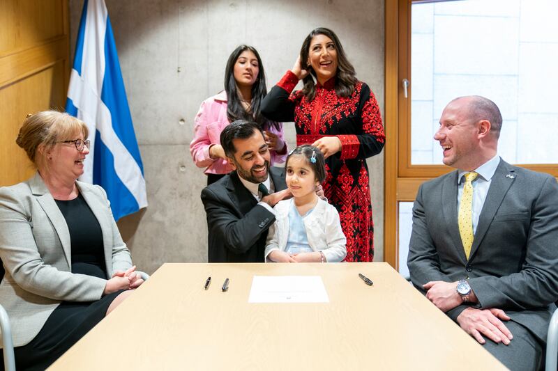 Mr Yousaf signs the nomination form to become First Minister of Scotland, watched by his wife Nadia El Nakla, daughter Amal and step-daughter Maya, in March 2023. Getty Images
