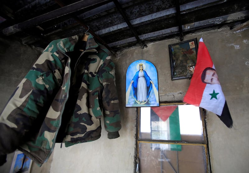 An army jacket, a picture of the Virgin Mary and a Syrian flag with Syria's President Bashar al-Assad are seen in a room in Damascus, Syria April 22, 2018. REUTERS/Ali Hashisho