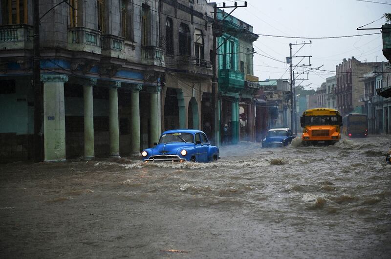 Old American cars and buses navigate a flooded street in Havana, Cuba. Heavy rains and malfunctioning sewers caused widespread flooding in the city.