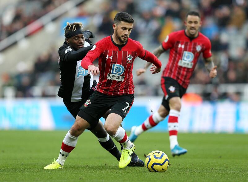 NEWCASTLE UPON TYNE, ENGLAND - DECEMBER 08: Shane Long of Southampton runs with the ball under pressure from Allan Saint-Maximin of Newcastle United during the Premier League match between Newcastle United and Southampton FC at St. James Park on December 08, 2019 in Newcastle upon Tyne, United Kingdom. (Photo by Nigel Roddis/Getty Images)