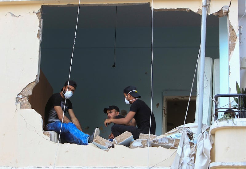 Men are seen sitting inside a damaged home, following Tuesday's blast in Beirut's port area. Reuters