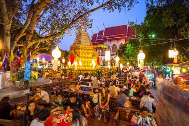 People sit outside Wat Phra Singh on market night. Courtesy iStockphoto.com