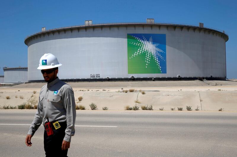 FILE PHOTO: An Aramco employee walks near an oil tank at Saudi Aramco's Ras Tanura oil refinery and oil terminal in Saudi Arabia May 21, 2018. Picture taken May 21, 2018. REUTERS/Ahmed Jadallah/File Photo