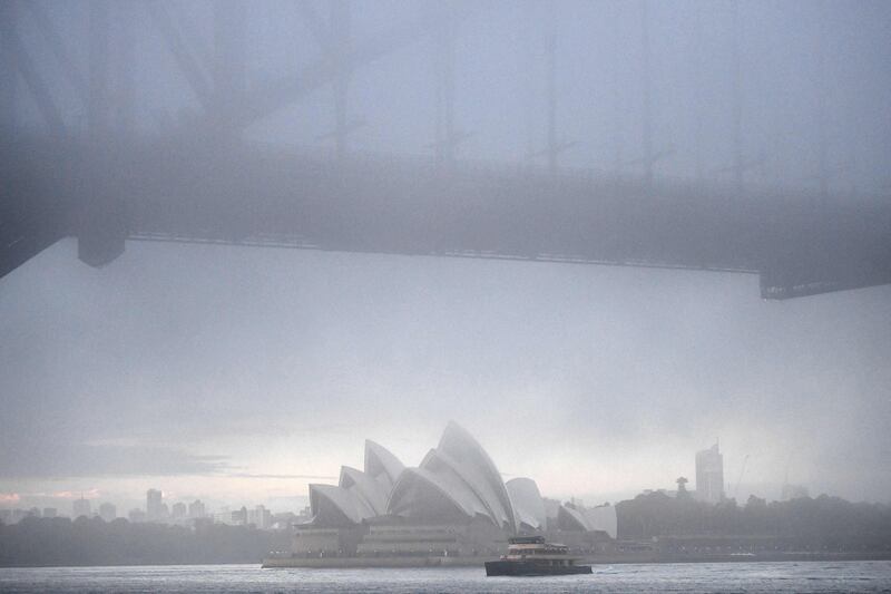 A ferry passes the Sydney Opera House as heavy fog blankets the city.