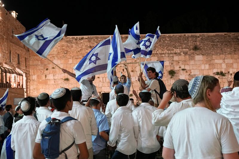Members of Israeli youth movements dance and wave flags. AP