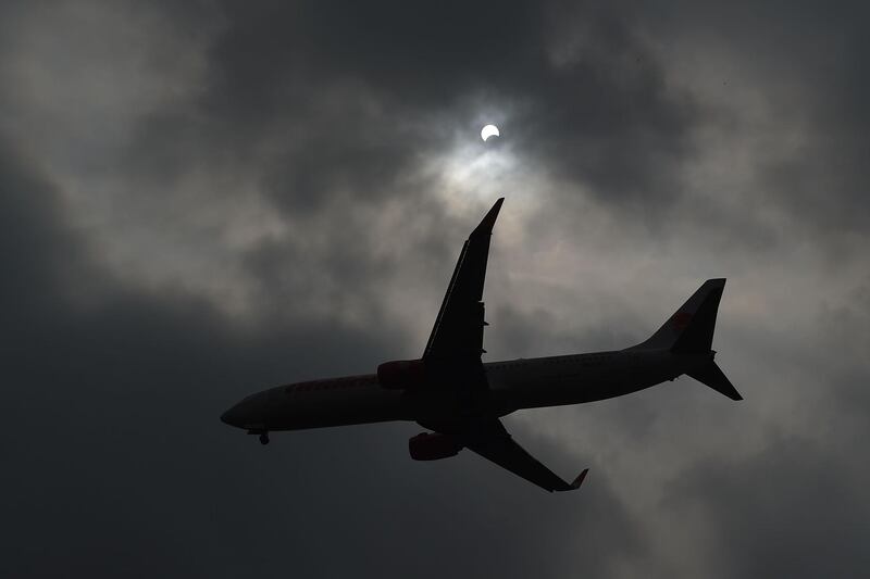 A plane flies past as the moon moves in front of the sun in Hanoi, Vienam. AFP