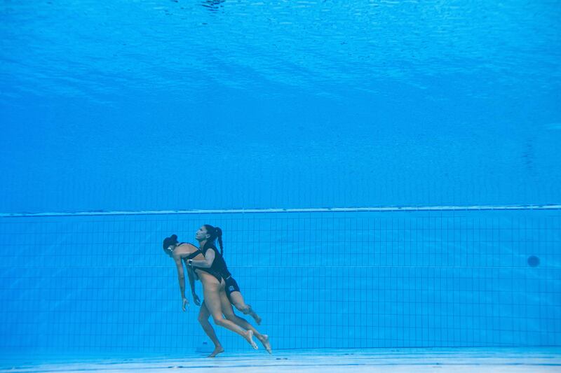 A member of Team USA goes to help Anita Alvarez who has fainted during the women's solo free artistic swimming finals. AFP