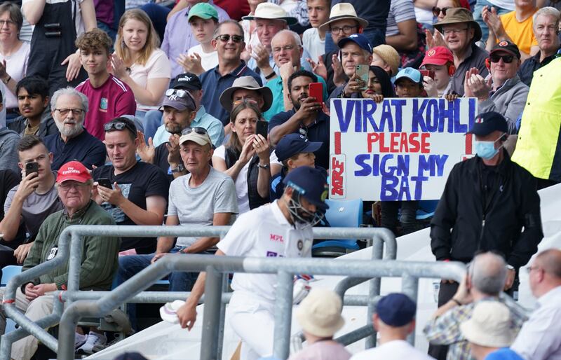 A young fan holds a placard as Virat Kohli walks back after losing his wicket. AP