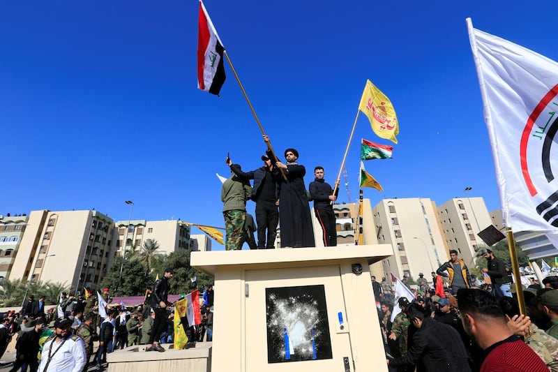 Protesters and militia fighters gather to condemn air strikes on bases belonging to the Popular Mobilisation Forces, an Iraqi umbrella group comprised of militia, some of which are pro-Iran,  outside the main gate of the US embassy in Baghdad. Reuters
