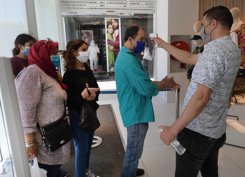 A clothing store employee measures the temperature of shoppers in the Tunisian capital Tunis.  AFP