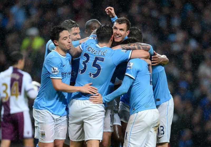 Manchester City striker Edin Dzeko, middle, is mobbed by teammates Samir Nasri, left, and Stevan Jovetic, centre, as well as others after he scored the side's first goal against Aston Villa on Wednesday. Andrew Yates / AFP / May 7, 2014