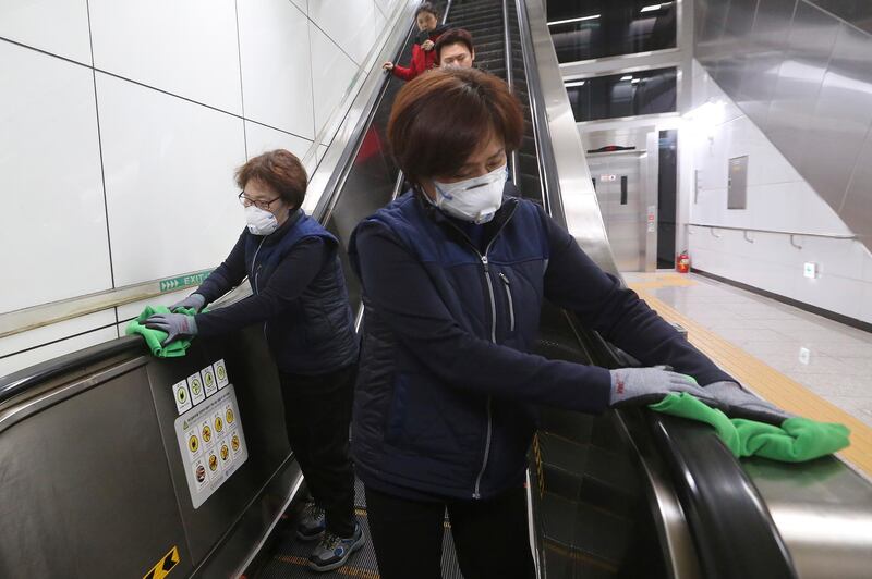 Employees disinfect escalator handrails in hopes to prevent transmission of the coronavirus at a subway station in Seoul, South Korea. AP Photo