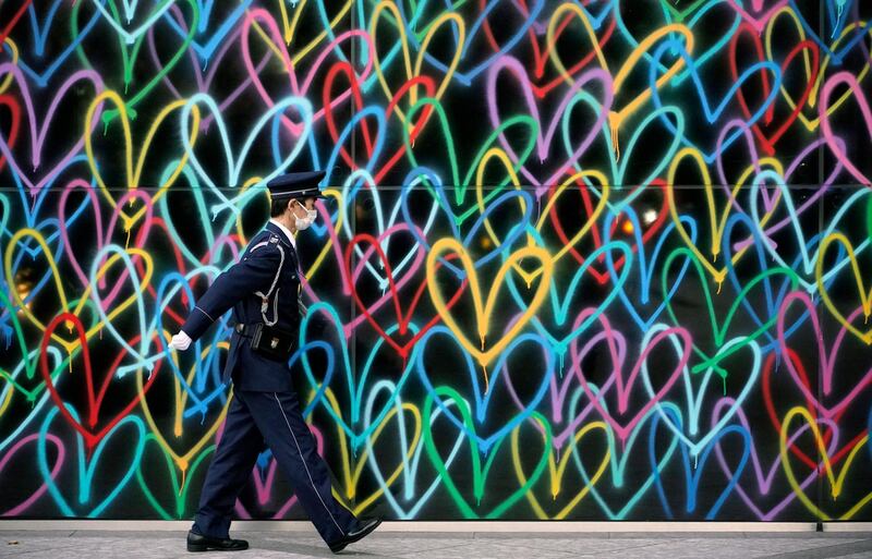 A security guard walks past a painted wall at a business district in Tokyo, Japan. The Tokyo Metropolitan Government announced that it has confirmed that 298 new people have been infected with the new coronavirus in Tokyo.  EPA