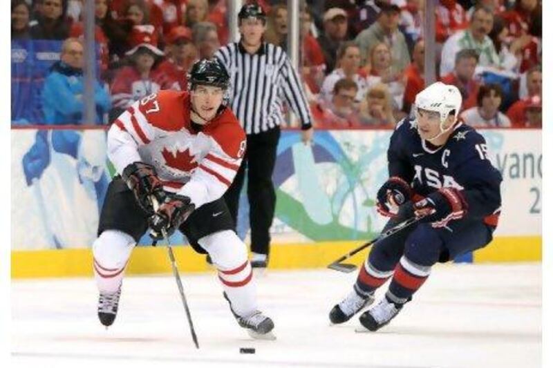 Sidney Crosby of Canada plays the puck through the neutral zone past Jamie Langenbrunner of USA during their men's gold medal game of Winter Olympics.